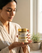 Woman holding a jar of chamomile sifted flower in a softly lit room.