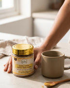 Jar of Deshna Golden Yellow Ajwain Bark Powder with a mug and spoon on a light surface.