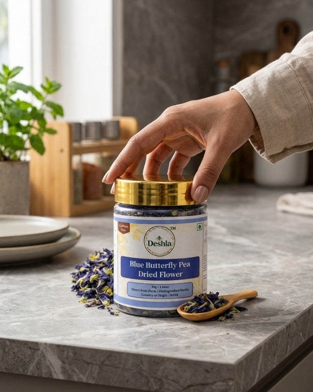 Hand opening a jar of Deshia Blue Butterfly Pea Dried Flower on a kitchen counter.