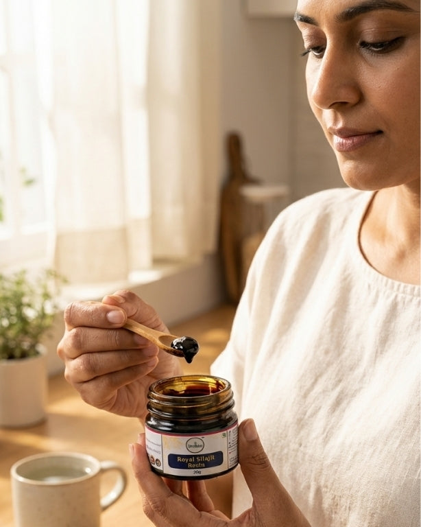 Woman holding a jar of honey with a wooden spoon indoors.
