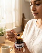 Woman holding a jar of honey with a wooden spoon indoors.