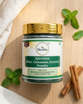Deshla Spirulina powder jar with mint leaves and cinnamon sticks on a wooden surface