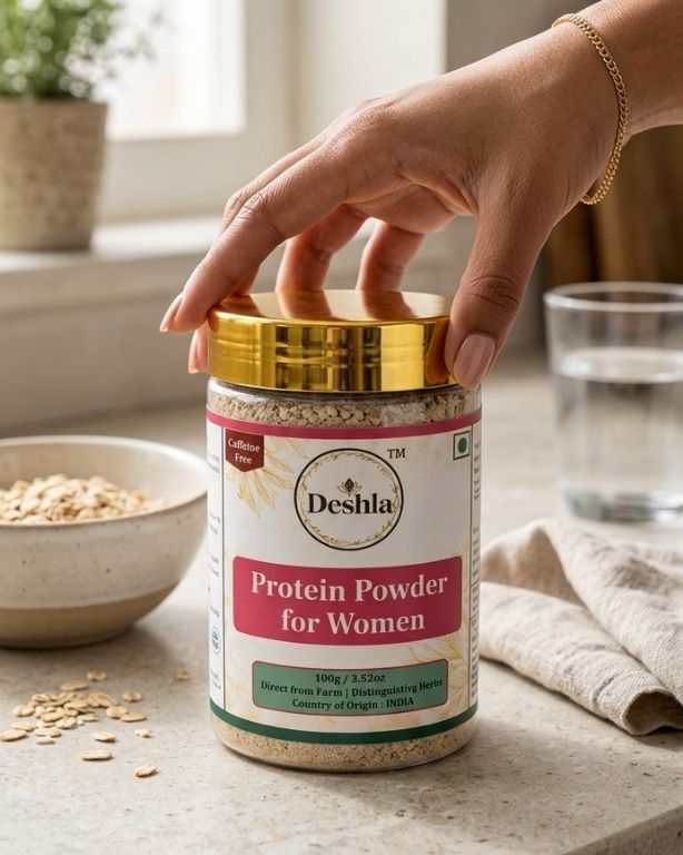 Deshla Protein Powder for Women jar with a hand holding it on a kitchen counter.
