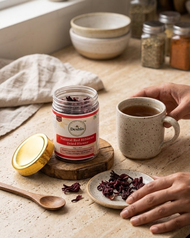 Person holding a cup of tea next to a jar of Doshla Red Hibiscus Drink Honey on a wooden surface.