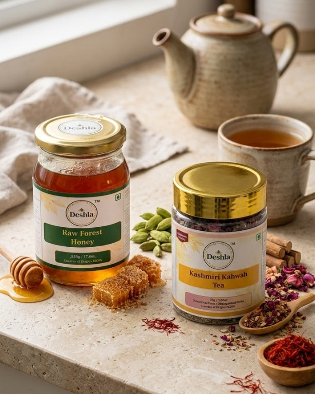 Two jars of Deshla honey and Kashmiri Kahwah tea on a table with a teapot and cup in the background.