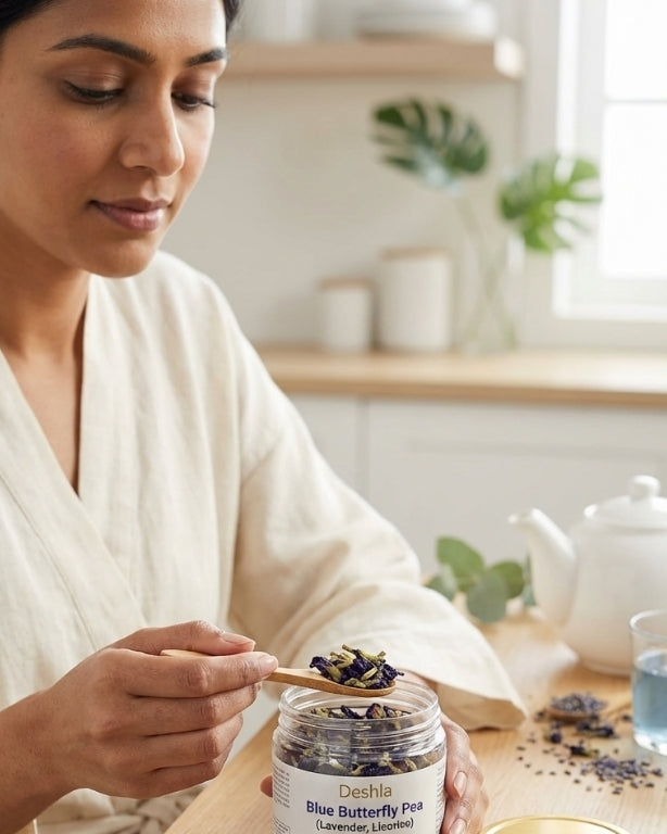 Woman in a white robe holding a jar of Doshisha Blue Butterfly Pea flowers in a kitchen setting.