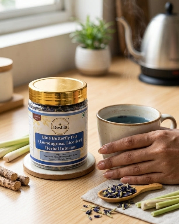 Deshla Blue Butterfly Pea herbal infusion jar on a wooden table with a cup of tea and tea leaves.