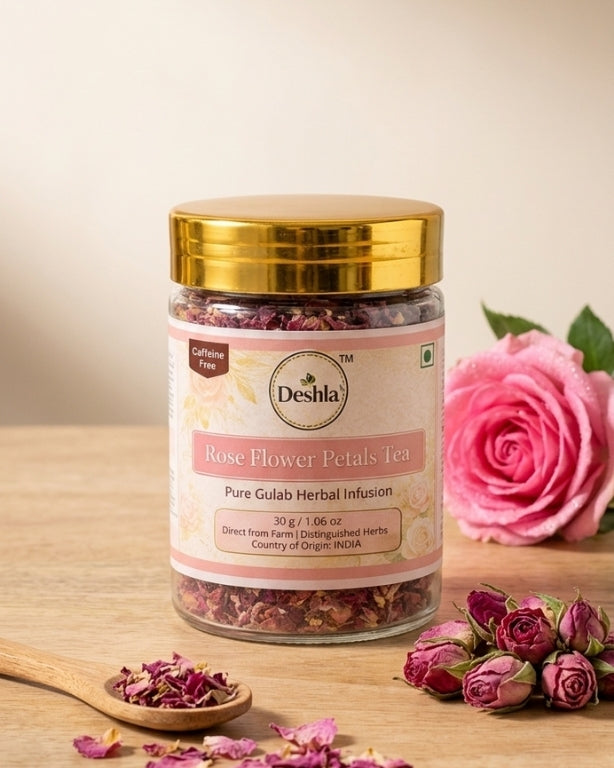 Jar of Deshla Rose Flower Petals Tea with a pink rose and tea leaves on a wooden surface.